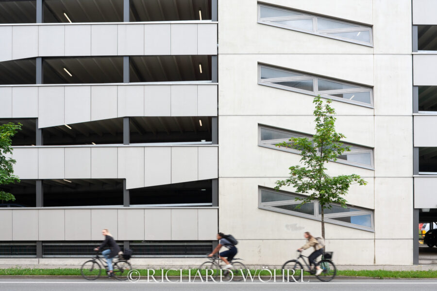 Drei Radfahrer vor Parkhausfassade