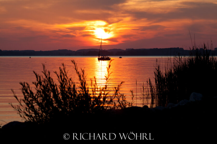 Segelboot vor der untergehenden Sonne am Chiemsee.